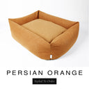 A warm amber orange Bliss Bolster Dog Bed in 'PERSIAN ORANGE' Faroe fabric shown from an angle on a white background, highlighting the tall sides of this long lasting dog bed with sides; a stylish bolster dog bed and high-wall dog bed for dogs of all sizes.