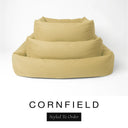 Three sizes of the Bliss Bolster Dog Bed in a warm golden mustard 'CORNFIELD' Faroe fabric nested together, showing this long lasting dog bed with sides in Small, Medium and Large; a hard-wearing bolster dog bed and high-wall dog bed for everyday comfort.