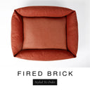 Top-down view of the Bliss Bolster Dog Bed in a warm terracotta orange-red 'FIRED BRICK' Faroe fabric, showing the raised sides and deep cushioned base of this long lasting dog bed with sides; a comfortable bolster dog bed and high-wall dog bed for everyday use.