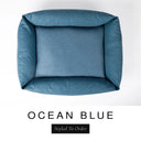 Top-down view of the Bliss Bolster Dog Bed in a deep petrol blue 'OCEAN BLUE' Faroe fabric, showing the raised sides and deep cushioned base of this long lasting dog bed with sides; a comfortable bolster dog bed and high-wall dog bed for everyday use.