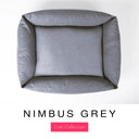 Top-down view of the Bliss Bolster Dog Bed in a cool blue-grey 'NIMBUS GREY' Faroe fabric, showing the raised sides and deep cushioned base of this long lasting dog bed with sides; a comfortable bolster dog bed and high-wall dog bed for everyday use.