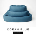 Three sizes of the Bliss Bolster Dog Bed in a deep petrol blue 'OCEAN BLUE' Faroe fabric nested together, showing this long lasting dog bed with sides in Small, Medium and Large; a hard-wearing bolster dog bed and high-wall dog bed for everyday comfort.