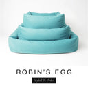 Three sizes of the Bliss Bolster Dog Bed in a soft powder blue 'ROBIN'S EGG' Faroe fabric nested together, showing this long lasting dog bed with sides in Small, Medium and Large; a hard-wearing bolster dog bed and high-wall dog bed for everyday comfort.