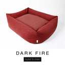 A deep rust red Bliss Bolster Dog Bed in 'DARK FIRE' Faroe fabric shown from an angle on a white background, highlighting the tall sides of this long lasting dog bed with sides; a stylish bolster dog bed and high-wall dog bed for dogs of all sizes.