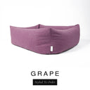 Close-up corner view of a dusky mauve-purple Bliss Bolster Dog Bed in 'GRAPE' Faroe fabric with a black 'Styled To Order' label, showing the tall walls of this long lasting dog bed with sides; a durable bolster dog bed and high-wall dog bed built to last.