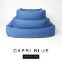 Three sizes of the Bliss Bolster Dog Bed in a rich denim blue 'CAPRI BLUE' Faroe fabric nested together, showing this long lasting dog bed with sides in Small, Medium and Large; a hard-wearing bolster dog bed and high-wall dog bed for everyday comfort.