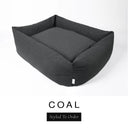 A dark charcoal black Bliss Bolster Dog Bed in 'COAL' Faroe fabric shown from an angle on a white background, highlighting the tall sides of this long lasting dog bed with sides; a stylish bolster dog bed and high-wall dog bed for dogs of all sizes.
