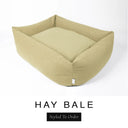 A warm golden oat Bliss Bolster Dog Bed in 'HAY BALE' Faroe fabric shown from an angle on a white background, highlighting the tall sides of this long lasting dog bed with sides; a stylish bolster dog bed and high-wall dog bed for dogs of all sizes.