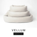 Three sizes of the Bliss Bolster Dog Bed in a soft off-white cream 'VELLUM' Faroe fabric nested together, showing this long lasting dog bed with sides in Small, Medium and Large; a hard-wearing bolster dog bed and high-wall dog bed for everyday comfort.