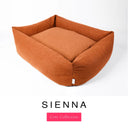 A warm burnt orange Bliss Bolster Dog Bed in 'SIENNA' Faroe fabric shown from an angle on a white background, highlighting the tall sides of this long lasting dog bed with sides; a stylish bolster dog bed and high-wall dog bed for dogs of all sizes.