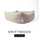Close-up corner view of a warm sandy taupe Bliss Bolster Dog Bed in 'DRIFTWOOD' Faroe fabric with a black 'Styled To Order' label, showing the tall walls of this long lasting dog bed with sides; a durable bolster dog bed and high-wall dog bed built to last.