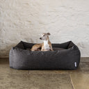 Box style dog bed with high sides in a hard-wearing, durable dark brown fabric with a dog sitting inside the lxuury bolster dog bed looking calm and content.