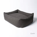 The luxury Bliss Bolster Dog Bed by Charley Chau made with a durable and hard-wearing upholstery fabric in a dark brown/black colour on a white backdrop. 