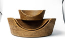 A stack of three round rattan dog baskets woven with natural rattan to create a contemporary wicker dog bed.