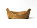 Front view of a contemporary rattan dog basket woven with natural rattan peel as a round dog basket with a sloping opening for dogs to step in easily.